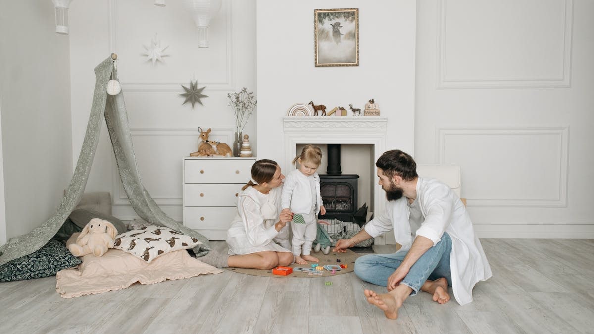 Warm family scene of parents playing with their daughter in a cozy white room.